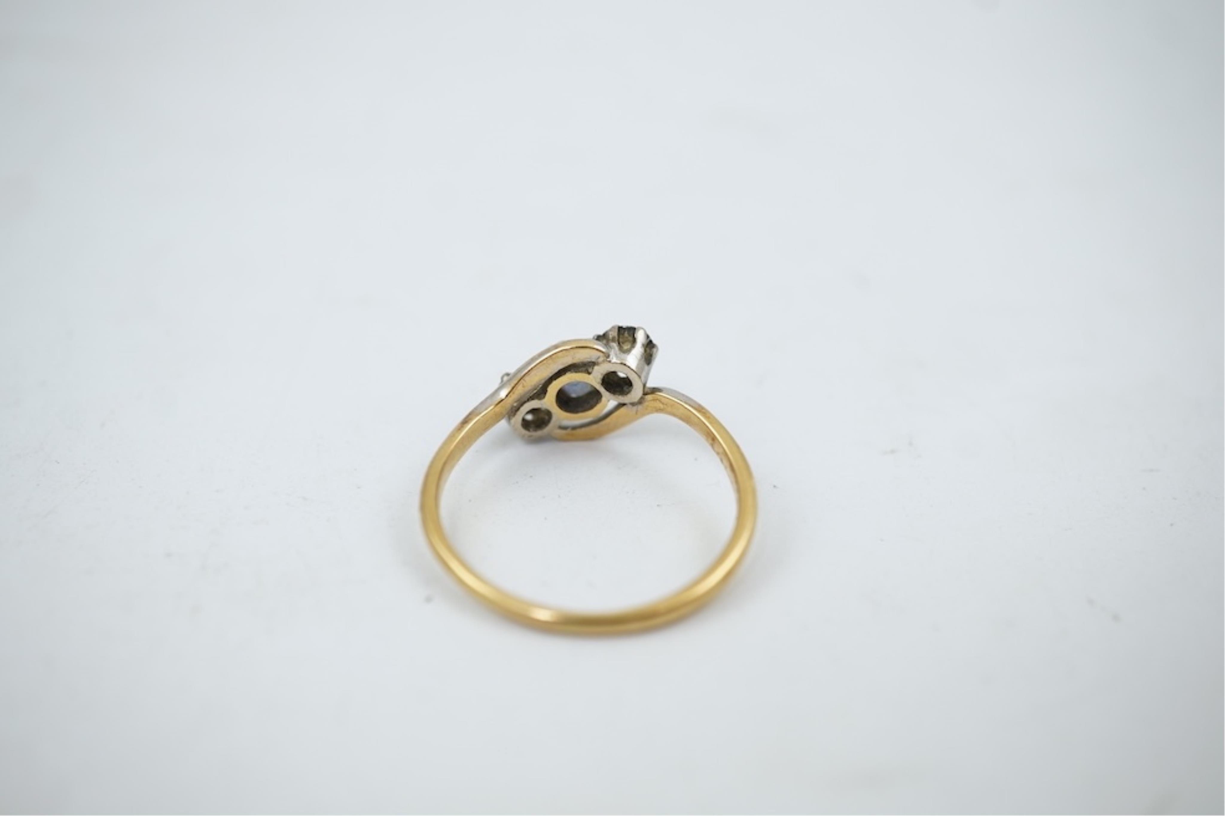 An early 20th century 18ct gold, sapphire and diamond set three stone crossover ring, size P/Q, gross weight 2.4 grams.